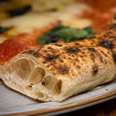 Närbild på fluffig kantbit av våra hemmagjorda napolitanska pizzor